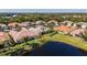 Aerial view of home with tile roof situated on a meticulously maintained lawn with lake view at 16233 Amethyst Key Dr, Wimauma, FL 33598