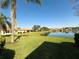 Beautiful backyard view overlooking a serene lake, lush green grass, and mature palm trees at 16233 Amethyst Key Dr, Wimauma, FL 33598