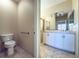 Well-lit bathroom featuring a double sink vanity, a toilet, and a tiled shower area at 16233 Amethyst Key Dr, Wimauma, FL 33598