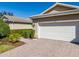 Home exterior featuring a brick driveway, two car garage, and well-maintained landscaping at 16233 Amethyst Key Dr, Wimauma, FL 33598