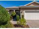 Charming front exterior showcasing a two-car garage, brick driveway, and meticulously landscaped walkway at 16233 Amethyst Key Dr, Wimauma, FL 33598