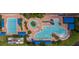 Aerial shot of a luxurious pool area with multiple pools, lounge chairs, umbrellas, and well-maintained landscaping for relaxation and fun at 16233 Amethyst Key Dr, Wimauma, FL 33598