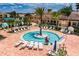 Scenic pool area with a circular shallow pool, surrounded by lounge chairs, palm trees, and well-maintained landscaping under a bright sky at 16233 Amethyst Key Dr, Wimauma, FL 33598