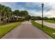 Paved walking path with mature landscaping and nearby roadway at 16233 Amethyst Key Dr, Wimauma, FL 33598