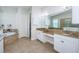 Bathroom featuring double sinks with granite countertops, white cabinetry, and a soaking tub in the background at 8319 Swiss Chard Cir, Land O Lakes, FL 34637