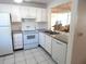 Condo kitchen with white cabinets, appliances, and gray countertops at 14130 Rosemary Ln # 2102, Largo, FL 33774