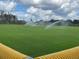 Water sprinklers watering the community ball field on a sunny day, seen from behind home plate at 5011 Sandy Brook Cir, Wimauma, FL 33598