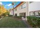 Exterior side of the apartment featuring manicured bushes and a red tiled roof at 1753 Belleair Forest Dr # E2, Belleair, FL 33756