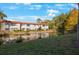 Exterior view of the apartment complex featuring mature trees and a pond at 1753 Belleair Forest Dr # E2, Belleair, FL 33756