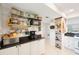 Well-organized kitchen pantry area with white cabinets, black counters, shelving, and food storage at 1753 Belleair Forest Dr # E2, Belleair, FL 33756