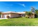 Tan one-story house with attached garage, well-maintained lawn, and tropical landscaping at 3276 Buckhorn Dr, Clearwater, FL 33761