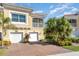 Tan two-story townhome with two-car garage, balcony, and tropical landscaping at 4284 Expedition Way, Osprey, FL 34229