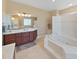 Well-lit bathroom featuring a soaking tub, vanity with modern fixtures, and tile flooring at 11213 Warm Wind Way, Weeki Wachee, FL 34613