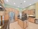 Spacious kitchen featuring stainless steel refrigerator and oven, light wood cabinets, and center island at 11213 Warm Wind Way, Weeki Wachee, FL 34613