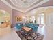 Bright living room with blue corner sofa, coffered ceiling, arched doorways, and decorative front doors at 11213 Warm Wind Way, Weeki Wachee, FL 34613