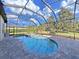 Screened-in pool with a clear blue water, spa, and lush landscaping, creating a private oasis at 11213 Warm Wind Way, Weeki Wachee, FL 34613