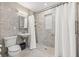 Clean bathroom with a shower and a toilet. Features white tile, storage and grab bars at 3637 63Rd N St, St Petersburg, FL 33710