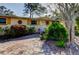 Bright yellow house with a brick driveway and tropical landscaping at 1747 Douglas Ave, Dunedin, FL 34698