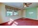 Living room with red carpet, ceiling fan, and a painted green accent wall at 1747 Douglas Ave, Dunedin, FL 34698