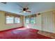 Bright living room with red carpet, ceiling fan, and two windows at 1747 Douglas Ave, Dunedin, FL 34698