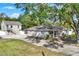 Front view of a house with a long driveway and large tree at 205 W 122Nd Ave, Tampa, FL 33612