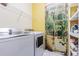 Bright laundry room featuring modern washer and dryer, with shelving for storage and a decorative nature scene door at 1105 Savannah Landings Ave, Valrico, FL 33596