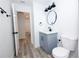 Bathroom with gray vanity, round mirror, and white door; wood-look floors at 3508 E 24Th Ave, Tampa, FL 33605