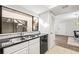 Modern kitchen featuring sleek black countertops and stainless steel sink, complemented by white cabinets and backsplash at 155 Nina Way, Oldsmar, FL 34677