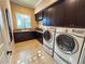 Bright laundry room with dark cabinetry, granite countertop, and full-size washer/dryer at 8376 Catamaran Cir, Lakewood Ranch, FL 34202