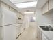 Galley kitchen with white appliances and light wood cabinets at 1034 Bowsprit Ln, Holiday, FL 34691