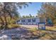 Light blue single-wide manufactured home with a gravel driveway and mature landscaping at 9615 Xenia St, New Port Richey, FL 34654