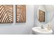 Close-up of a half bath featuring modern sink, round mirror and decorative wooden leaf artwork at 4653 Pleasant Ave, Palm Harbor, FL 34683