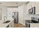 Modern kitchen with stainless steel appliances, white cabinets, and a stylish backsplash at 17938 Solstice Ave, Venice, FL 34293