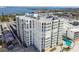 Aerial view of a beachfront condo building with pool and tennis courts at 4950 Gulf Blvd # 206, St Pete Beach, FL 33706