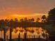 Stunning sunset over a calm lake with palm trees reflected in the water at 5205 Covesound Way, Apollo Beach, FL 33572