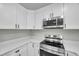 Modern kitchen featuring white cabinets, stainless steel appliances, and quartz countertops at 9126 109Th Ter, Seminole, FL 33777