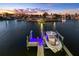 Waterfront home at dusk with a boat lift featuring blue LED lighting at 17410 1St E St, Redington Shores, FL 33708