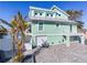 Stylish waterfront home featuring a light green exterior, balcony, and well-manicured landscaping at 17410 1St E St, Redington Shores, FL 33708