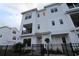 Three-story townhome with white siding, black windows, and a small front yard at 7244 Sutton Ln, Sarasota, FL 34240