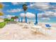 Patio area furnished with white tables, chairs, and blue umbrellas overlooking the beach at 16308 Gulf Blvd # 303, Redington Beach, FL 33708