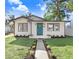 Charming bungalow with teal front door, landscaping, and walkway at 1227 E Mohawk Ave, Tampa, FL 33604