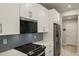 Modern kitchen with white cabinets, gray tile backsplash, and stainless steel appliances at 31464 Woodland Race Loop, Wesley Chapel, FL 33545