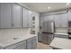 Gray shaker cabinets, stainless steel appliances, and white quartz countertops in this modern kitchen at 31471 Woodland Race Loop, Wesley Chapel, FL 33545