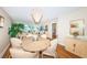 Bright dining room with round table and seating for four, hardwood floors, and a large chandelier at 7100 Sunset Way # 205, St Pete Beach, FL 33706