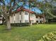 Exterior view of condo building with lush landscaping and a well-maintained lawn at 1753 Belleair Forest Dr # F3, Belleair, FL 33756