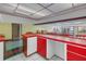 Basement bar with red and white cabinetry and views into the recreation area at 5200 62Nd S Ave, St Petersburg, FL 33715