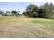 Spacious grassy backyard with a home and trees in the distance at 7424 Lance St, Zephyrhills, FL 33541