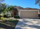 Tan two-story house with palm trees, attached garage, and landscaped yard at 1638 Sand Hollow Ln, Valrico, FL 33594