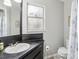 Bathroom with black vanity, sink, toilet, and window; neutral gray walls and light wood flooring at 14160 82Nd Ter, Seminole, FL 33776