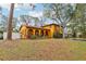 A wide shot showing the mature trees surrounding this charming yellow home with tile roof at 14160 82Nd Ter, Seminole, FL 33776